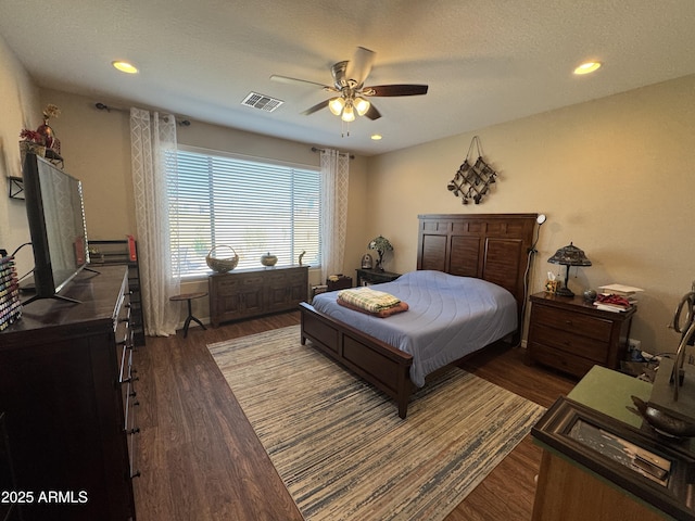 bedroom with ceiling fan, dark wood-type flooring, and a textured ceiling