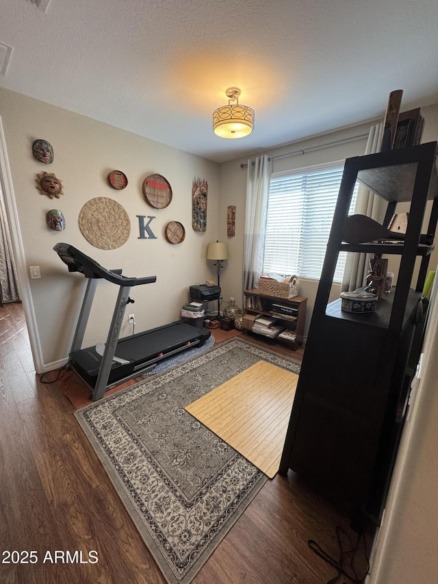 workout area featuring dark hardwood / wood-style floors and a textured ceiling