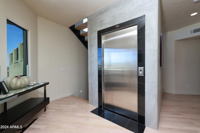 interior space featuring elevator and light hardwood / wood-style flooring