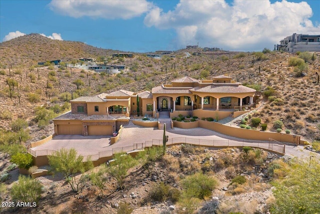 view of front of home with a garage, fence, a mountain view, and stucco siding