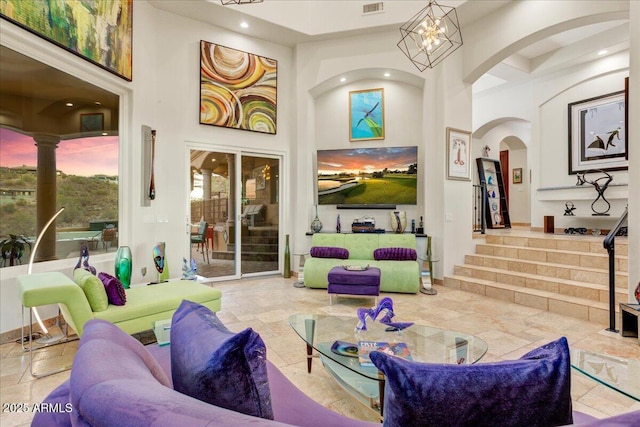 living area featuring a towering ceiling, stairs, stone tile flooring, and recessed lighting