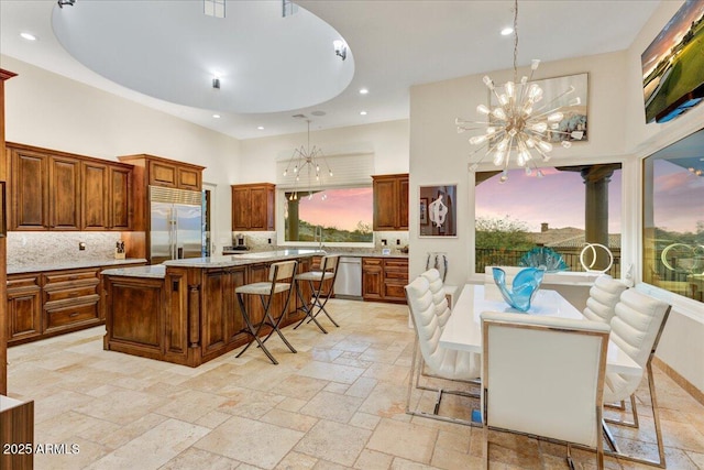 kitchen featuring appliances with stainless steel finishes, stone tile flooring, a high ceiling, and an inviting chandelier