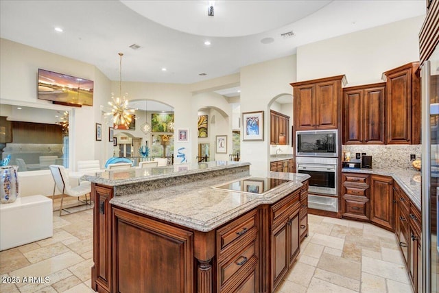 kitchen with tasteful backsplash, open floor plan, stone tile floors, and light stone countertops