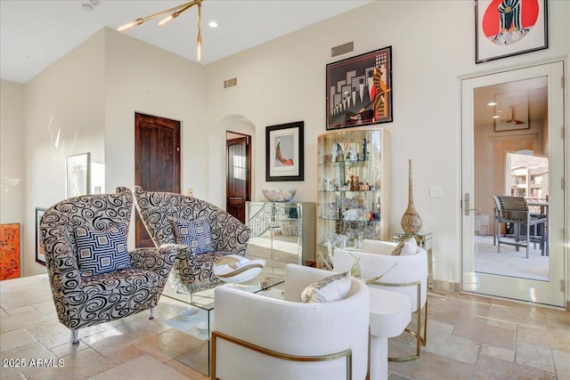 living area with arched walkways, stone tile flooring, visible vents, and recessed lighting