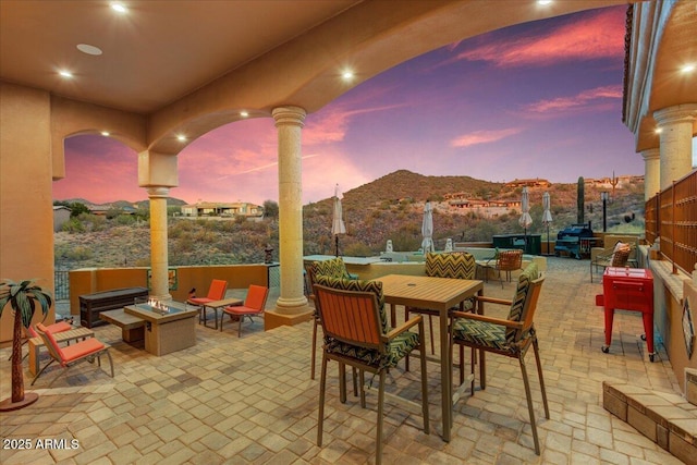 view of patio with a fire pit, outdoor dining area, and a mountain view