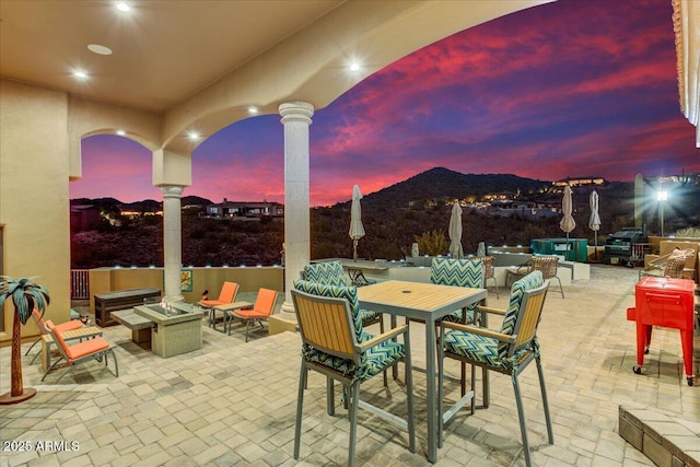 view of patio / terrace with outdoor dining area, a mountain view, and a fire pit