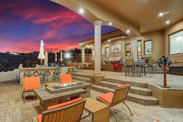 patio terrace at dusk with an outdoor fire pit and outdoor dry bar