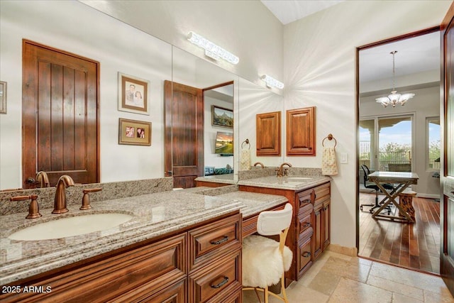 bathroom featuring a chandelier, stone tile flooring, and vanity