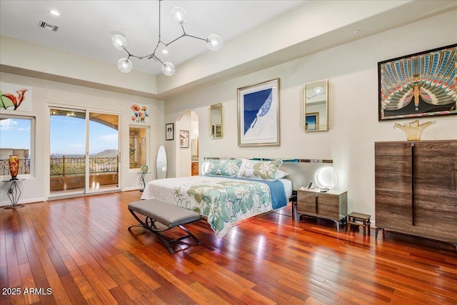 bedroom featuring baseboards, visible vents, arched walkways, hardwood / wood-style flooring, and access to exterior