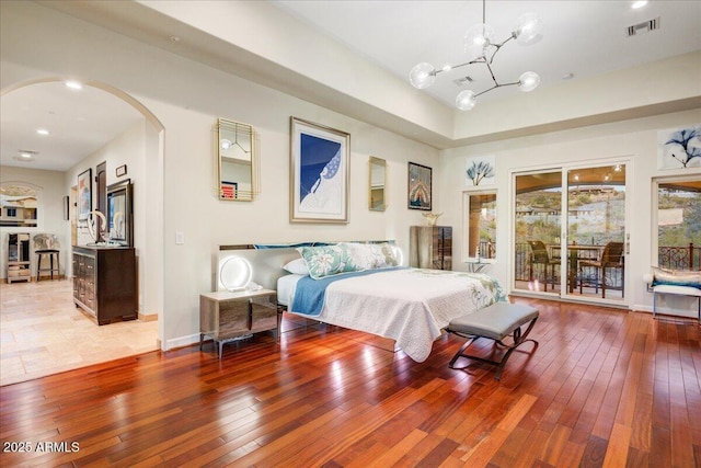 bedroom featuring access to exterior, arched walkways, visible vents, and hardwood / wood-style flooring