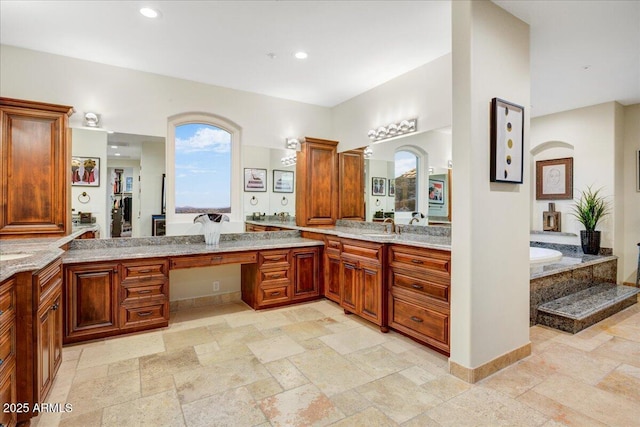 full bathroom with stone tile flooring, a garden tub, vanity, and recessed lighting