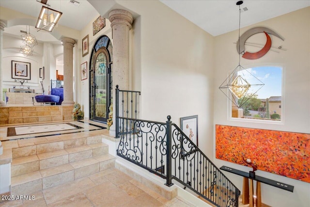 corridor featuring stone tile flooring, an upstairs landing, and decorative columns