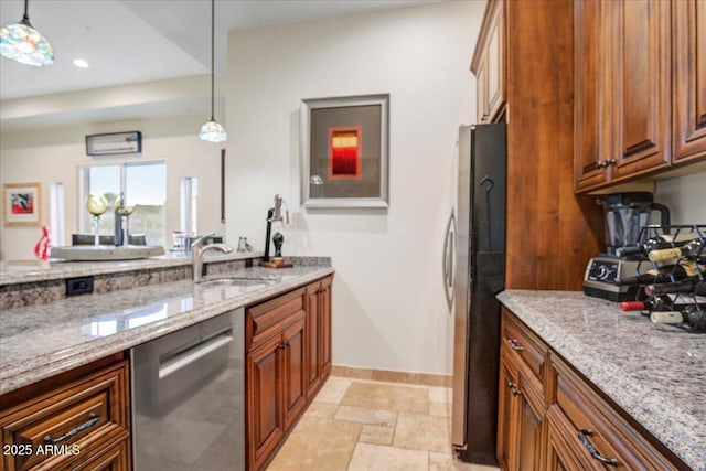 kitchen with stainless steel appliances, a sink, light stone countertops, brown cabinetry, and pendant lighting