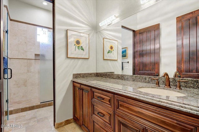 full bathroom featuring a shower stall, baseboards, and vanity