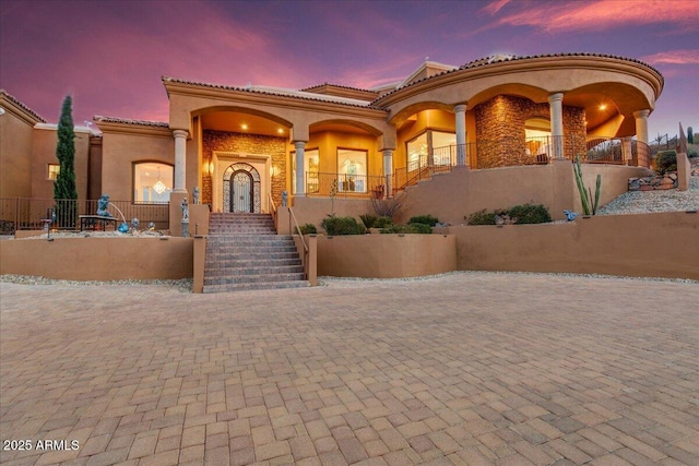 mediterranean / spanish-style home featuring stairs, a tile roof, a porch, and stucco siding