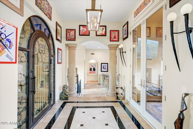 corridor featuring arched walkways, french doors, baseboards, and ornate columns