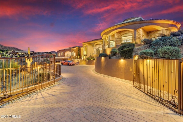 mediterranean / spanish house featuring a residential view, a gate, fence, and stucco siding