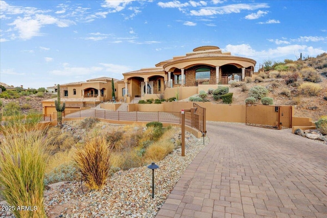 view of front facade with driveway, fence, a gate, and stucco siding