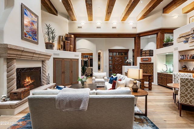 living room with beamed ceiling, a towering ceiling, and light hardwood / wood-style flooring