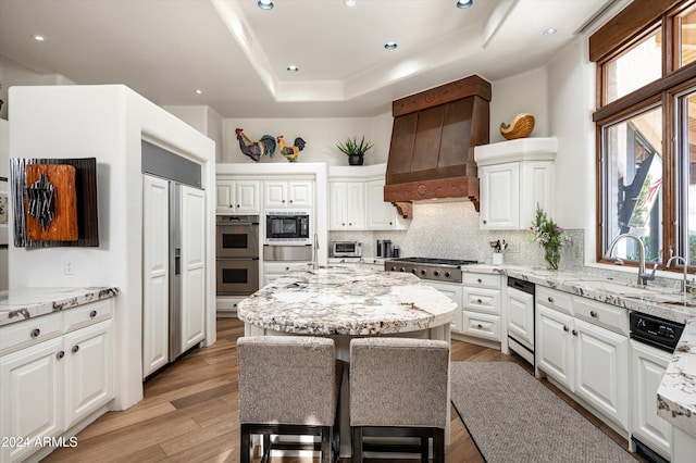 kitchen featuring light stone counters, a center island, white cabinets, and stainless steel appliances