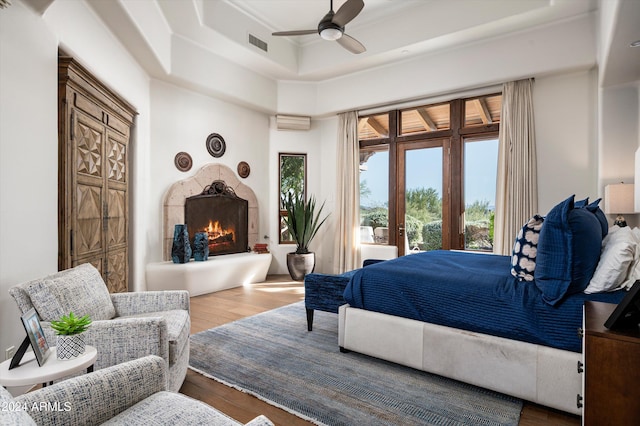 bedroom featuring ceiling fan, a raised ceiling, and wood-type flooring