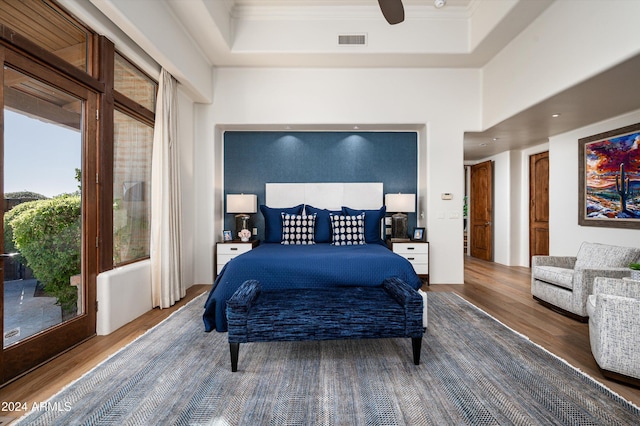 bedroom featuring hardwood / wood-style floors, ceiling fan, crown molding, and a tray ceiling