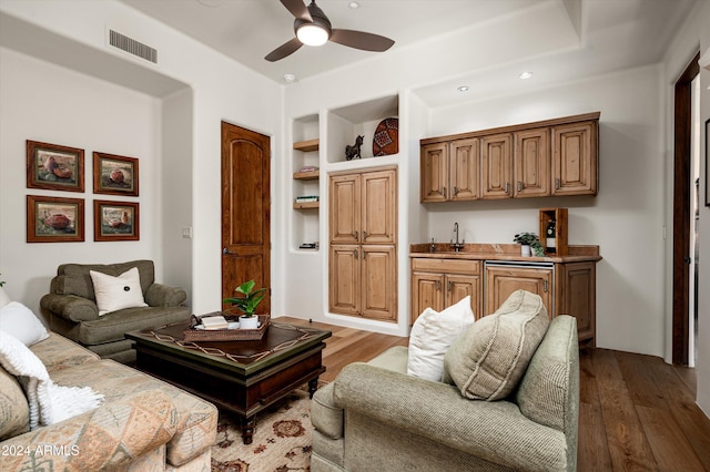 living room with built in shelves, ceiling fan, light wood-type flooring, and indoor bar