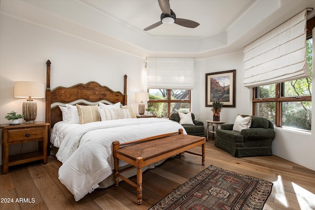 bedroom with hardwood / wood-style floors, a raised ceiling, and ceiling fan