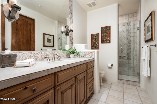 bathroom featuring tile patterned flooring, vanity, toilet, and a shower with door