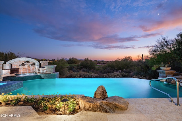 pool at dusk featuring pool water feature