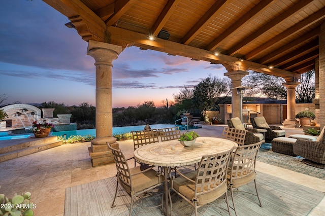 patio terrace at dusk featuring pool water feature