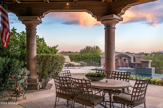 patio terrace at dusk featuring pool water feature