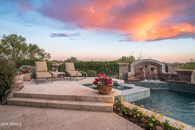 patio terrace at dusk featuring pool water feature and a swimming pool with hot tub