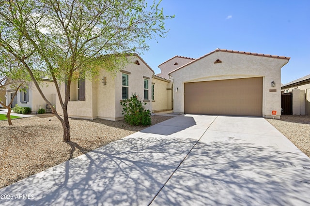 mediterranean / spanish home featuring fence, driveway, stucco siding, a garage, and a tiled roof