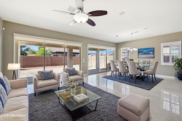 living area with tile patterned floors, ceiling fan with notable chandelier, baseboards, and visible vents