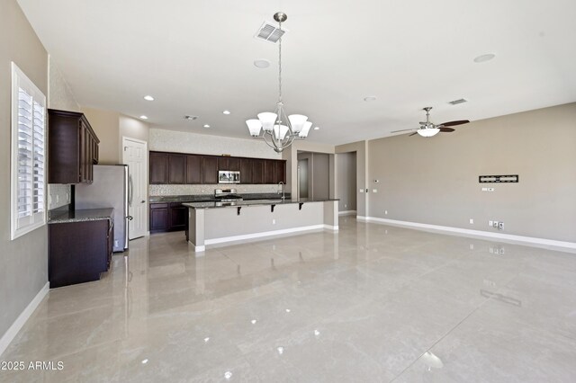 kitchen featuring visible vents, open floor plan, dark brown cabinetry, appliances with stainless steel finishes, and baseboards