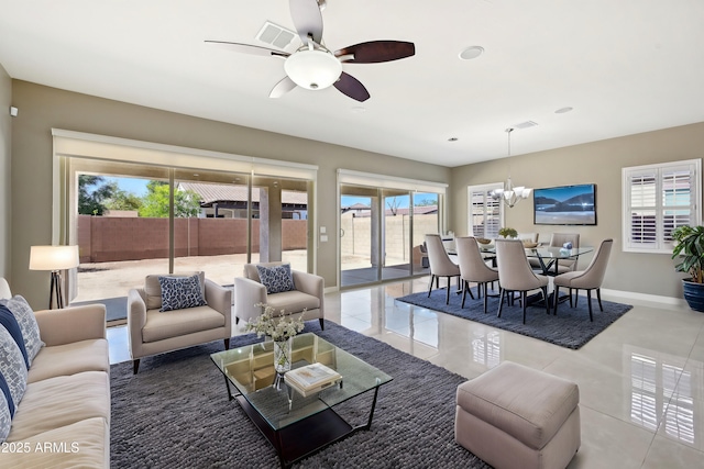 tiled living room with ceiling fan with notable chandelier and baseboards