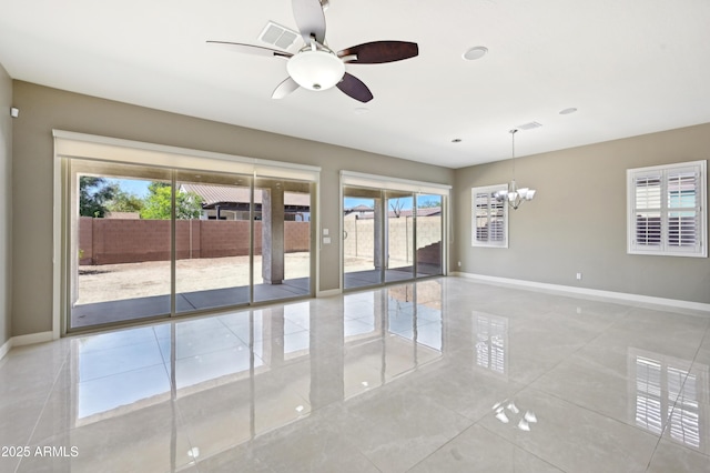 spare room featuring baseboards and ceiling fan with notable chandelier