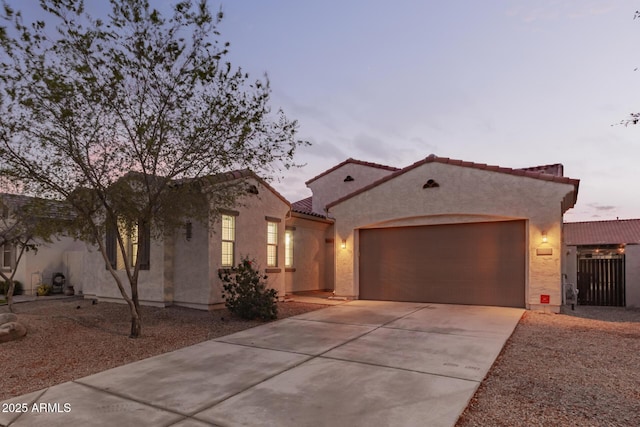 mediterranean / spanish house with stucco siding, driveway, a tile roof, and a garage