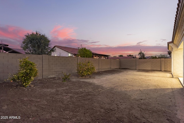 yard at dusk featuring a fenced backyard