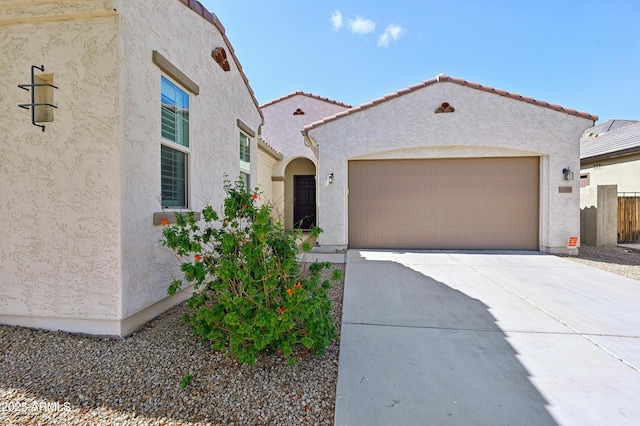 mediterranean / spanish-style house featuring stucco siding, a garage, concrete driveway, and a tiled roof