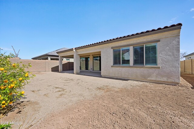 rear view of house with a patio area, a tile roof, a fenced backyard, and stucco siding