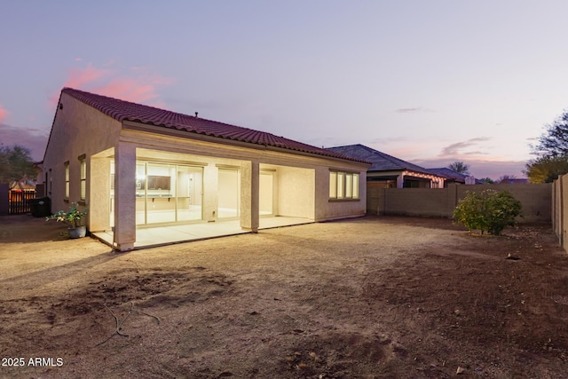 rear view of property with stucco siding, a patio, a tile roof, and a fenced backyard