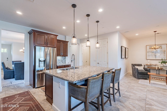 13719 W Amberwing St, Peoria, AZ 85383 - kitchen with stainless steel fridge with ice dispenser, a chandelier, a sink, recessed lighting, and light stone countertops