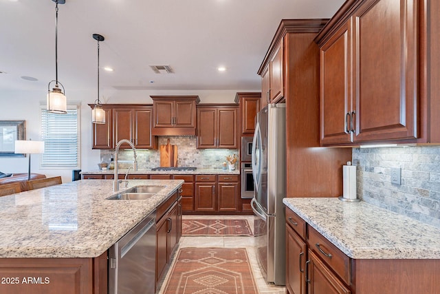 13719 W Amberwing St, Peoria, AZ 85383 - kitchen featuring stainless steel appliances, a sink, tasteful backsplash, light stone counters, and hanging light fixtures