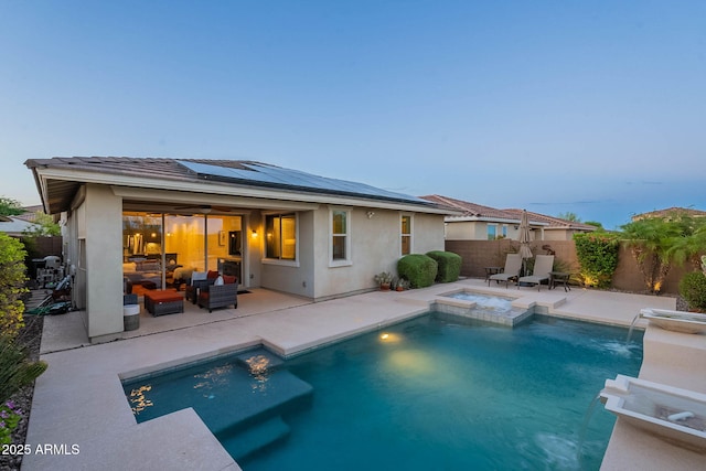 13719 W Amberwing St, Peoria, AZ 85383 - back of house at dusk featuring outdoor lounge area, roof mounted solar panels, a patio, a fenced backyard, and stucco siding