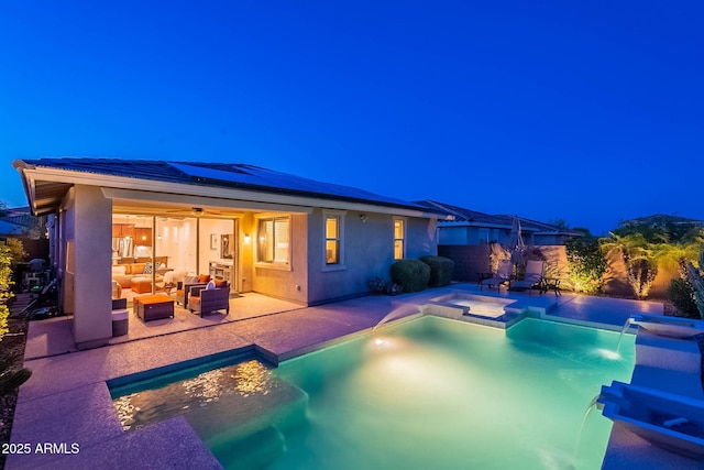13719 W Amberwing St, Peoria, AZ 85383 - pool at night featuring outdoor lounge area, a pool with connected hot tub, a ceiling fan, a patio, and a fenced backyard