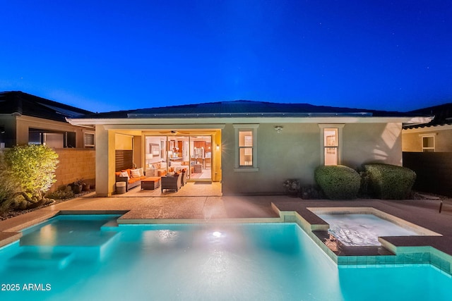 13719 W Amberwing St, Peoria, AZ 85383 - back of house at night with an outdoor living space, stucco siding, a patio area, a pool with connected hot tub, and ceiling fan