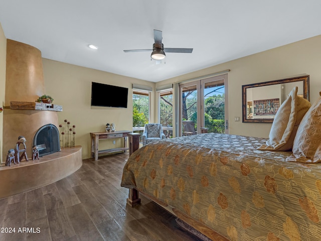 bedroom featuring hardwood / wood-style flooring, ceiling fan, a large fireplace, and access to outside