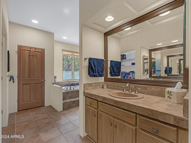 bathroom featuring tile patterned flooring, tiled tub, and vanity